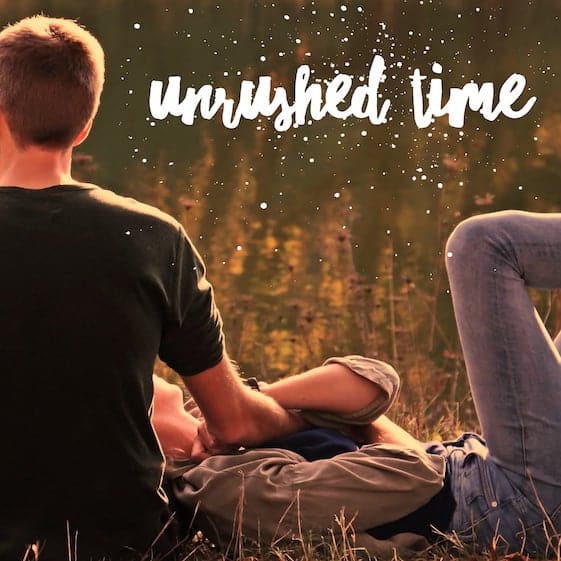 couple laying in grass relaxing with words unrushed time on image