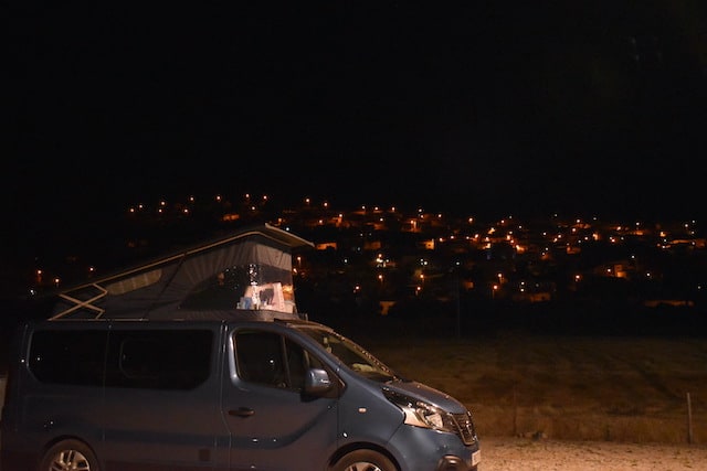 campervan in front of hill with street lights shining