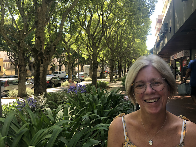 lady smiling in front of tree lined avenue