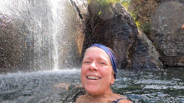 lady swimming under waterfall