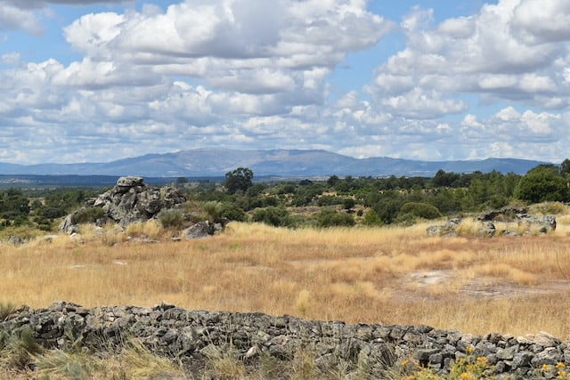 View of dry grass fields granite rocks and blue tinged mountains