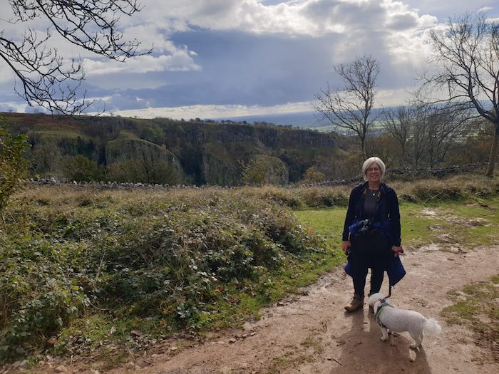 woman with white bichon frise dog walking in countryside