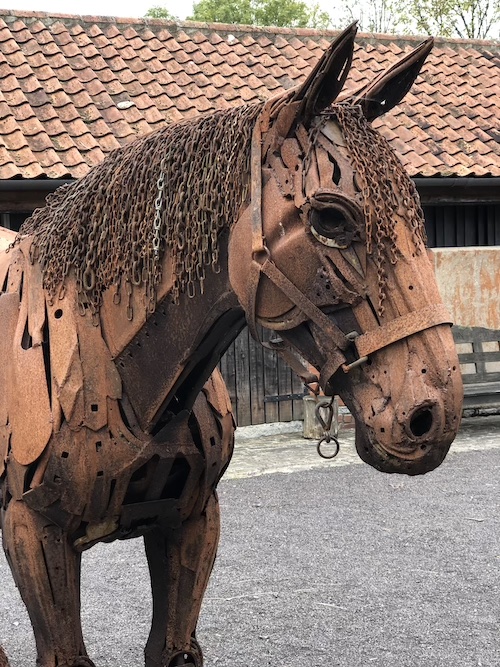 very lifelike horse sculpture constructed from rusted metal
