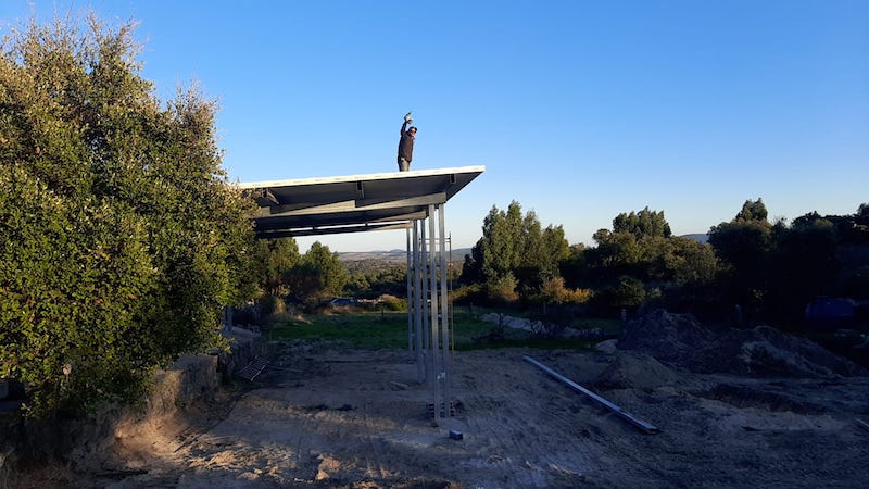 man standing on top of high roof shelter  waving