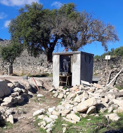 small concrete shed with pile of stones and rubble in front