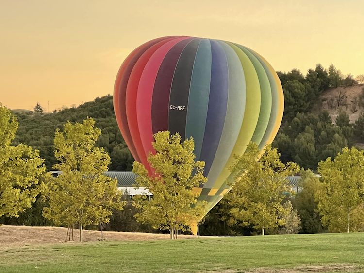 rainbow coloured hot air balloon on ground getting ready to rise